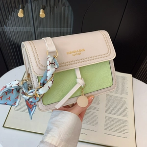 Detail of light green leather crossbody bag with silk scarf on gold chain strap