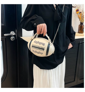 Detail view of cream rugby-shaped crossbody bag with gold chain and black stripes