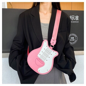 Gros plan sur le sac bandoulière guitare rose et blanc avec rivets et large bandoulière