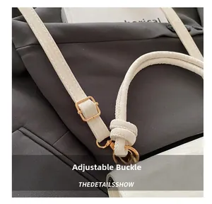Detailed close-up of white leather shoulder strap with golden adjustable buckle on a bag