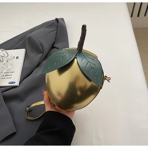 Détail du sac à bandoulière pêche doré miroir avec des feuilles en cuir vert réalistes