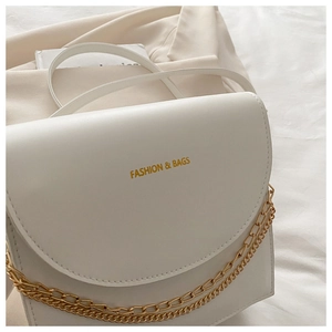 Détail d'un sac à rabat blanc en cuir avec chaîne dorée et inscription Fashion & Bags