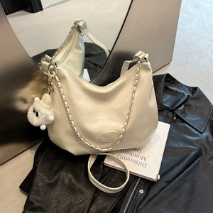 Creamy leather shoulder tote with chain strap and cute plush monster pendant on jacket