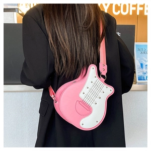 Détail d'un sac bandoulière rose en forme de guitare avec large bandoulière et rivets