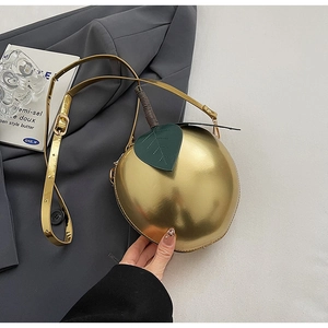 Détail du sac à bandoulière créatif en forme de pomme dorée avec feuille et tige verte