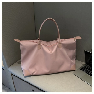 Bolsa de viaje rosa de gran capacidad junto a un portátil en un entorno moderno