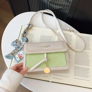 Detail of a chic square crossbody bag with silk scarf on a book, French style