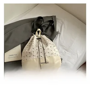 Detailed macro of cream pleated bag texture featuring bow pattern and HUANIKOU logo print