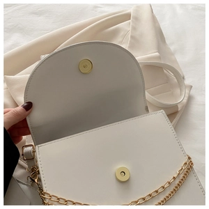 Détail du sac en similicuir blanc avec double chaîne dorée et fermoir magnétique rond