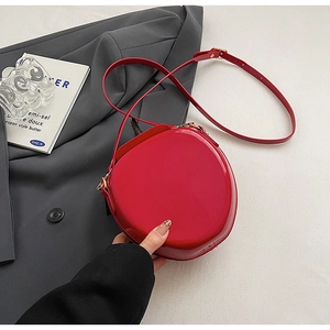 Détail du sac pastèque en cuir verni rouge avec finition brillante et ferrures dorées