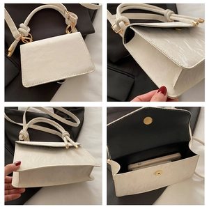 Detail view of cream-white textured mini bag with knotted handle and gold hardware accents
