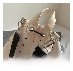 Detail of silver metal hook and black strap on white bow pattern embossed bag