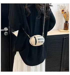 Close-up of a cream rugby-shaped crossbody bag with gold chain strap and embossed details