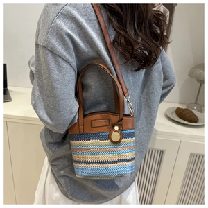 Detail showing the colorful woven straw bucket bag with leather handles and straps