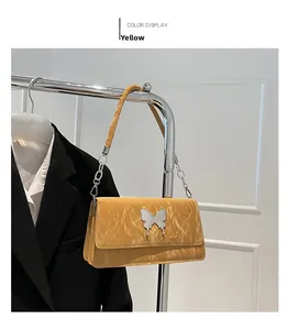 Detail of brown quilted bag with silver butterfly charm and metal chain link handle