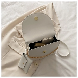 Détail intérieur du sac bandoulière en cuir blanc avec un téléphone et un portefeuille