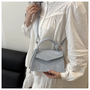 Detail of light blue pleated handbag featuring elegant metal hardware and adjustable strap