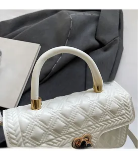 Close-up of heart-shaped metal lock and quilted leather texture on white handbag