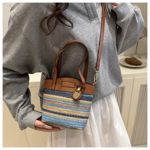 Macro shot of colorful striped woven straw bucket bag with premium brown leather details