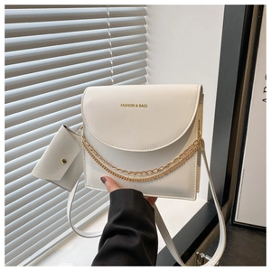 Détail du sac bandoulière en cuir blanc avec chaînes dorées et mini porte-monnaie