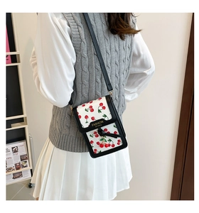 Detail view of a white leather crossbody bag with cherry prints and fashion lettering