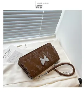 Detail of coffee brown wrinkled leather handbag with silver butterfly metal ornament