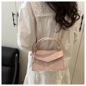 Detail of pink shoulder bag with unique crinkled paper texture and envelope flap closure