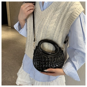 Close-up of stylish black round PU leather handbag with crocodile pattern texture
