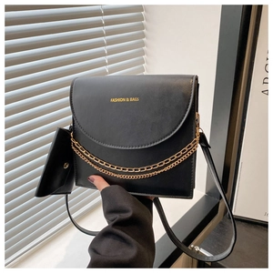 Détail d'un sac bandoulière en cuir noir avec chaîne dorée et mini pochette amovible