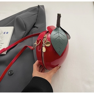Détail du sac rouge en forme de pomme avec feuille en cuir vert et zip doré