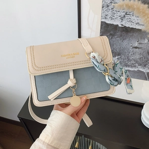 Detail of color-block crossbody bag with silk scarf handle and metal logo tag
