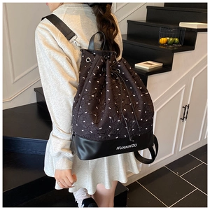 Detail of drawstring backpack showing white bow embroidery and reinforced leather base