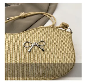 Macro detail of straw woven bag featuring silver metal bow and thick rope strap
