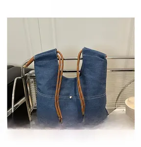 Detail of dark blue denim tote bag featuring rope handles and white contrast stitching