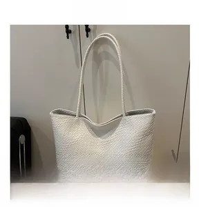 Close-up of white woven PU leather texture and sleek shoulder strap on the tote bag