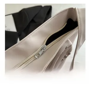 Close-up of smooth silver zipper and rivet details on creamy beige leather cloud bag
