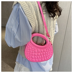 Vibrant pink round PU leather handbag with stone texture shown worn as a crossbody bag.