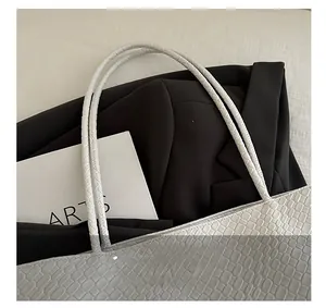 Detail showing white crocodile embossed leather texture on a minimalist tote handbag