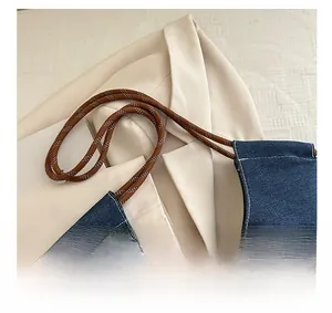 Detail of denim tote bag with contrast stitching and woven rope handle in macro view