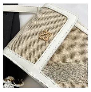 Macro detail of beige canvas texture with white leather trim and golden floral clasp