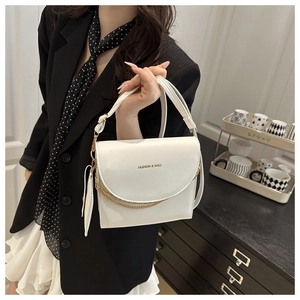 Détail du sac bandoulière en cuir blanc avec double chaîne dorée et fermeture à boucle