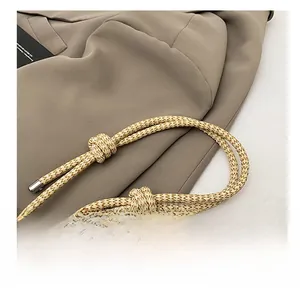Close-up of woven shoulder strap with beige and brown cords and silver metal tips