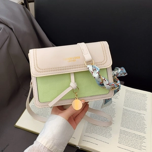 Detail of light green litchi grain crossbody bag with silk scarf handle and gold text