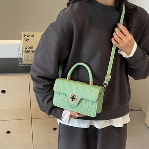 Mint green crossbody bag with elegant quilted pattern and clover metal lock on a model