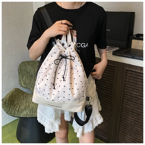 Detail of drawstring bucket bag with black bow patterns and branded leather trim