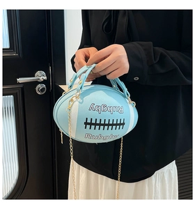 Detail of light blue rugby-shaped handbag featuring gold chain strap and embossed text