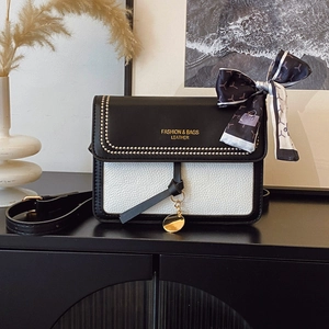 Detail of crossbody bag with studs, logo lettering, and a decorative silk scarf