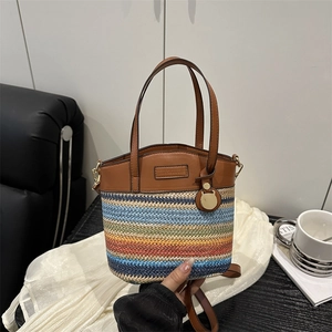 Fashionable rainbow straw bucket bag with brown leather handles and a gold cat charm
