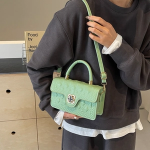 Detail of pistachio green quilted handbag with golden flower clasp and round handle
