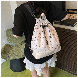 Detail of beige textured bubble fabric backpack with black bow prints and leather base
